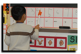 Boy uses pointer on number chart